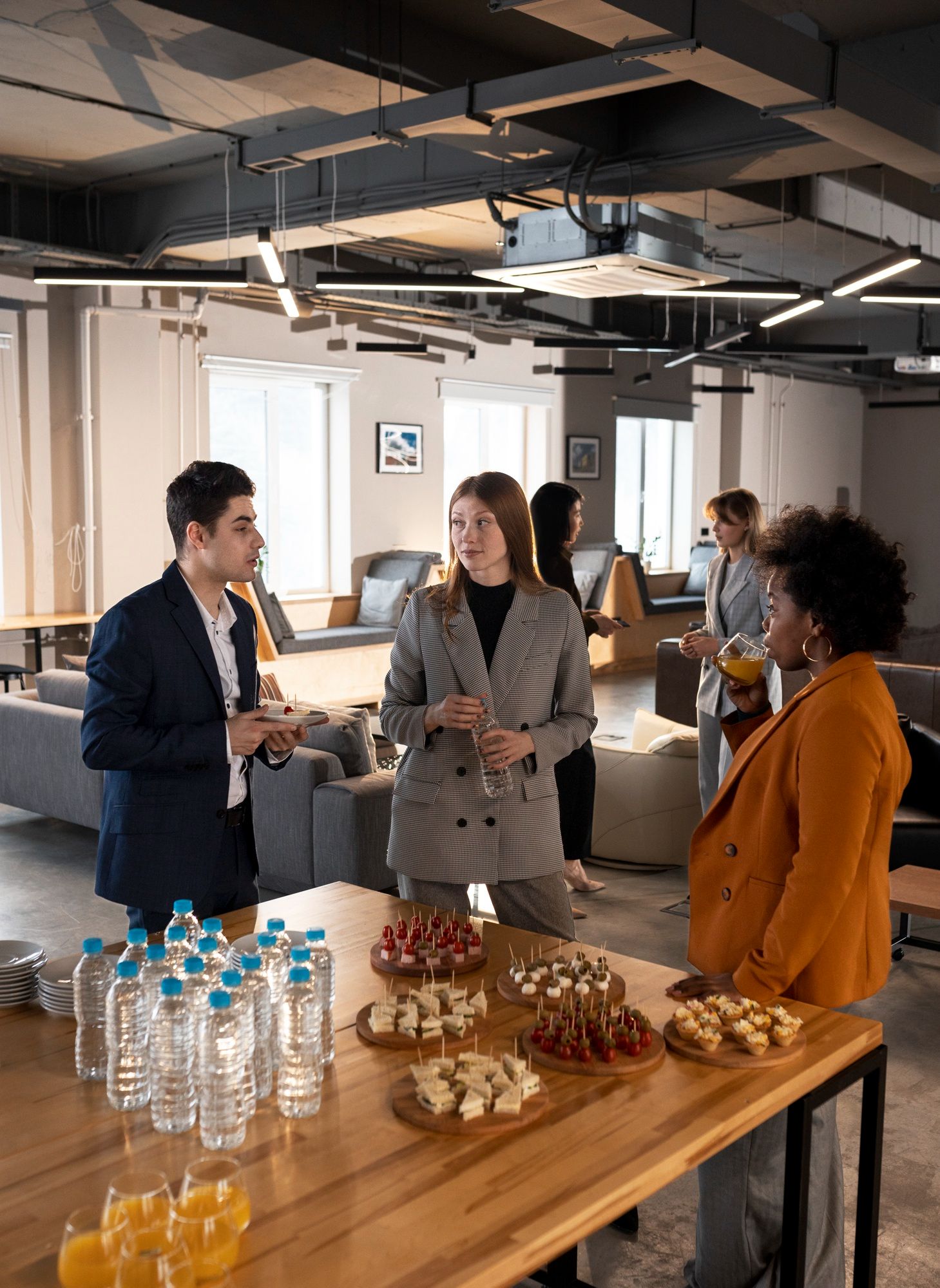 People at a networking event with drinks and food on a wooden table